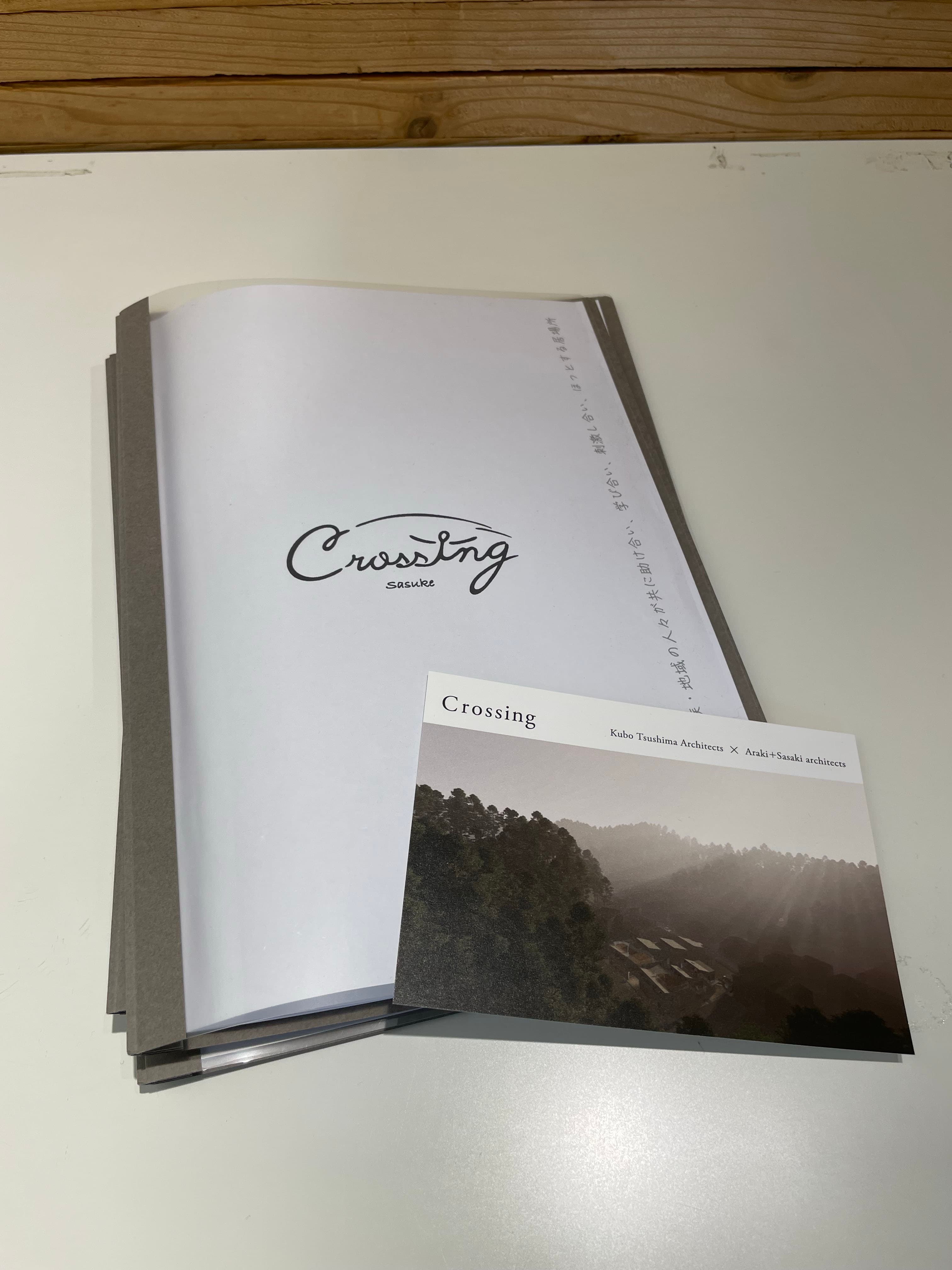 「Crossing sasuke」の企画書表紙と、山あいの集落を俯瞰した写真が使われた冊子
