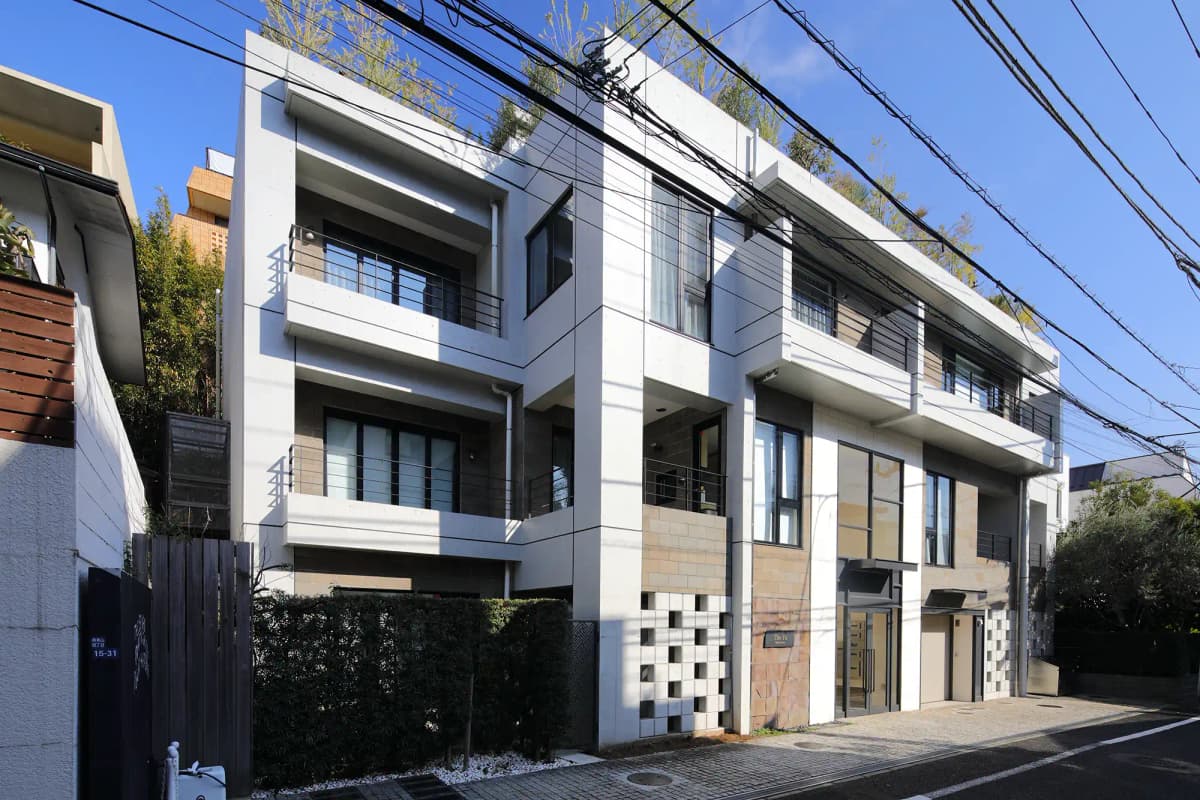 住宅街の一角に建つ、白を基調としたモダンな3階建て建築の外観。